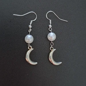 A pair of earrings featuring a round acrylic pearl in white and silver crescent moon charms