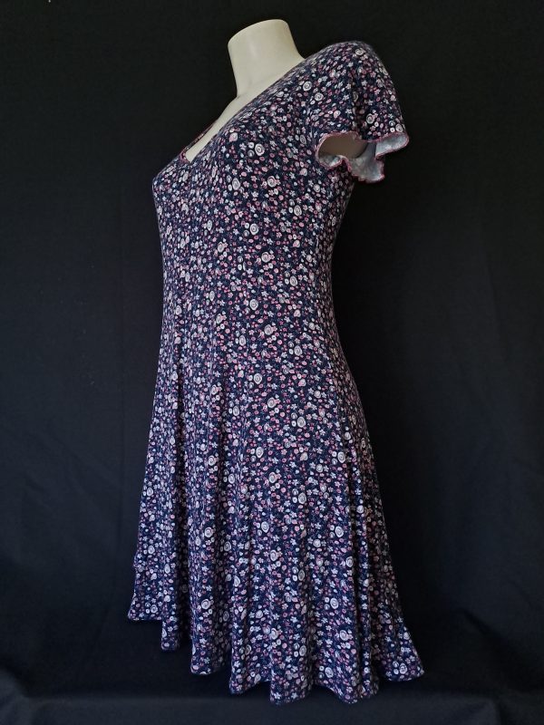 Casual floral dress with a V-neck and short sleeves, featuring pink and purple hues. Showcasing the back and silhouette.