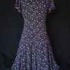 Casual floral dress with a V-neck and short sleeves, featuring pink and purple hues. Showcasing the back and silhouette.