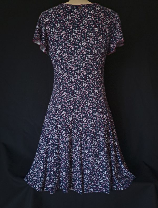 Casual floral dress with a V-neck and short sleeves, featuring pink and purple hues. Showcasing the back and silhouette.