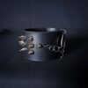Black leather wristband with stainless steel spikes in assymetrical placement. Intertwined rings forming a chain and connecting th center large steel o-ring. A unique twist to a classis alternative fashion accessory of gothic or punk styles.