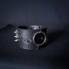 Black leather wristband with stainless steel spikes in assymetrical placement. Intertwined rings forming a chain and connecting th center large steel o-ring. A unique twist to a classis alternative fashion accessory of gothic or punk styles.